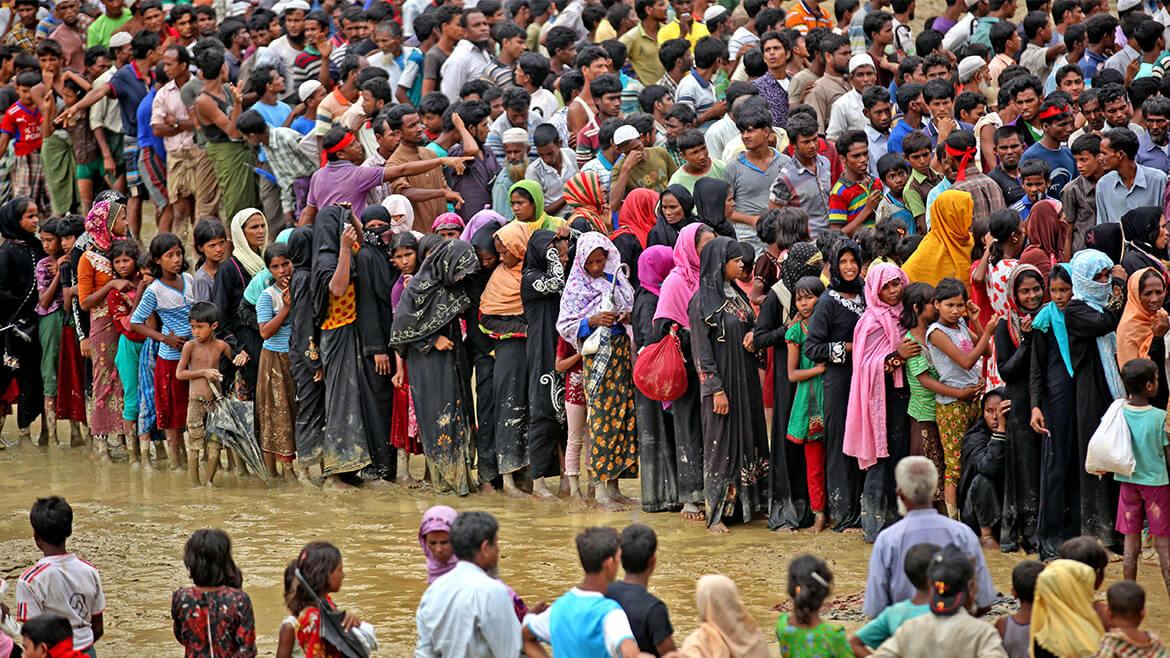 Flucht und Vertreibung der Rohingya, 2017: Die Vertreibung der muslimischen Rohingya aus Myanmar gehört zu den jüngsten Zwangsmigrationen. Viele retten sich in das Nachbarland Bangladesch. Dort leben sie in bitterer Armut, häufig in großen Flüchtlingslagern, wie hier in Kutupalong, einem der größten Lager der Welt, mit hunderttausenden Menschen. Auf diesem Bild warten Flüchtlinge in einer langen Schlange vor der Essensausgabe.