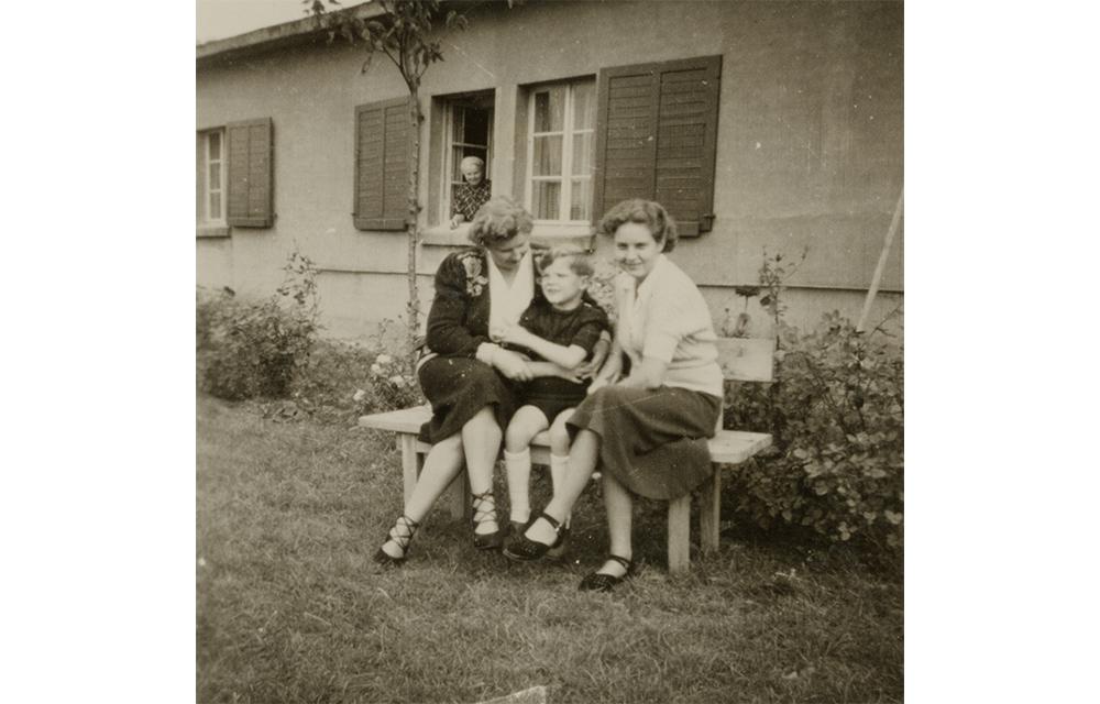 Die drei Paetsch-Kinder sitzen gemeinsam vor ihrer umgebauten Baracke in Salzgitter-Watenstedt, in der sie ab Dezember 1947 mit ihren Eltern, der Großmutter und dem Hausmädchen leben.